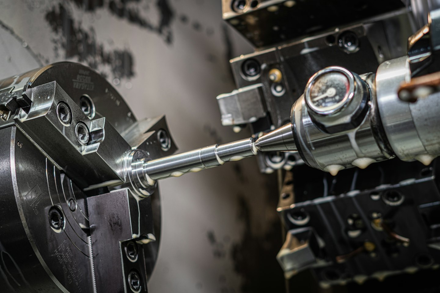 CNC lathe precisely machining a shiny metal rod with coolant dripping.